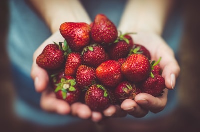 草莓在人手掌上的浅聚焦摄影